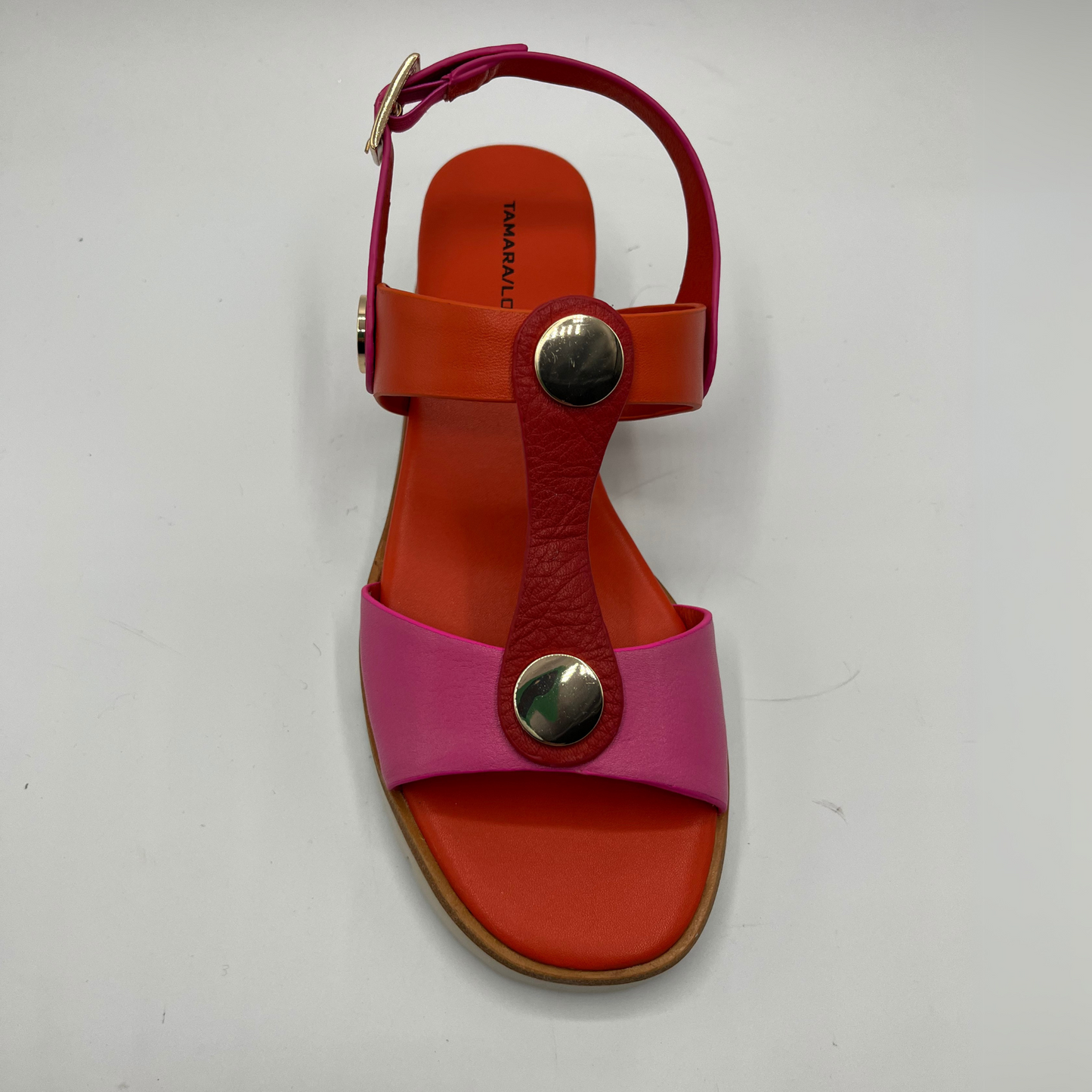 Top view of a fuschia and orange leather sandal with a wedge heel, adjustable ankle strap and shiny gold details.