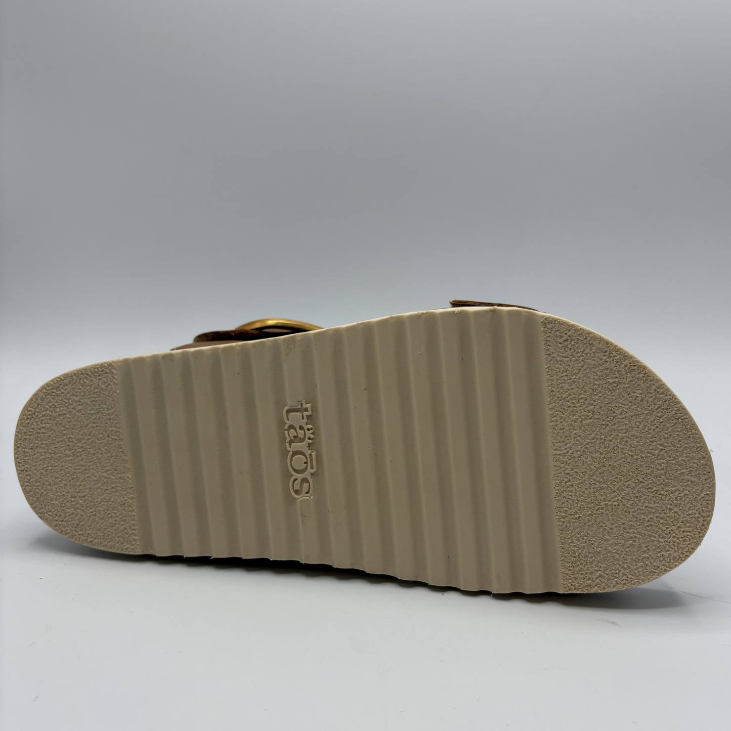 Tan sandal sole with 'Toms' branding on a gray background