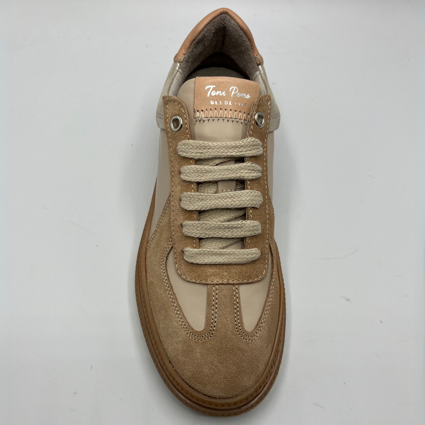 Tan sneaker with visible brand name on a white background