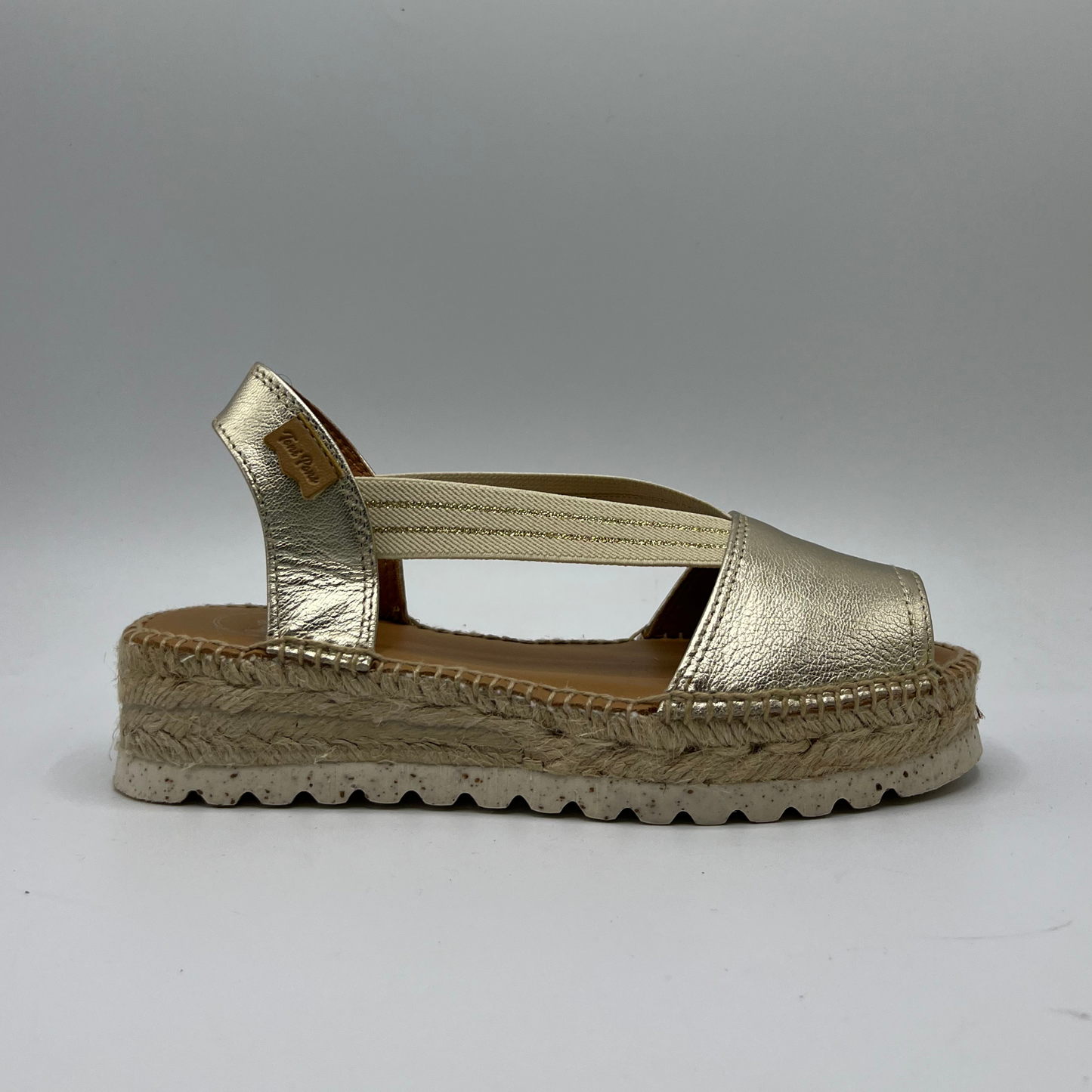 Right facing view of an espadrille soled sandal with elasticated side straps and platinum leather straps.