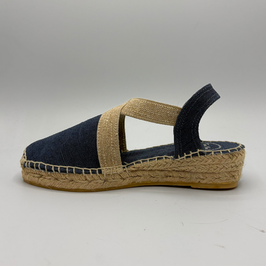 Navy blue espadrille sandal with a brown sole on a gray background