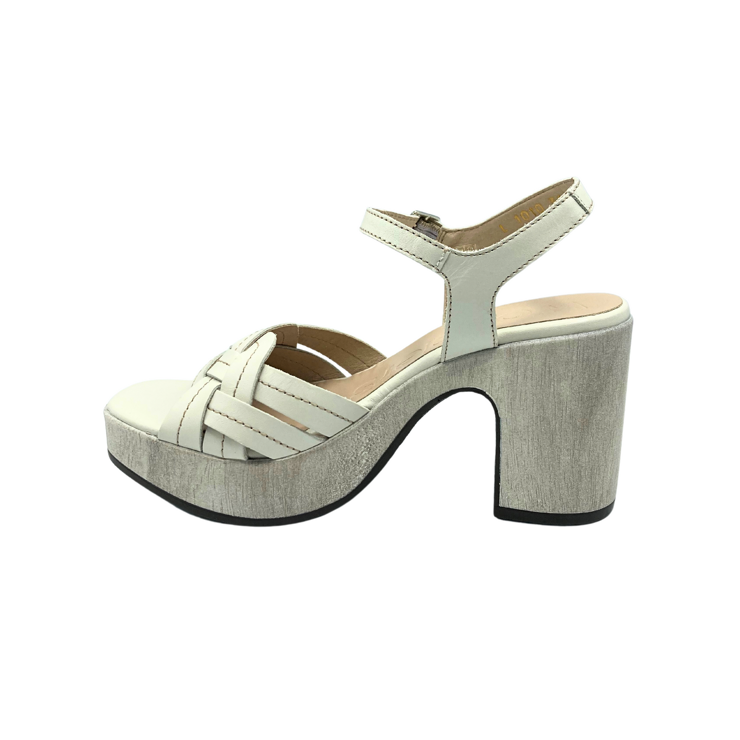 Inside view of a platform sandal. Creamy white leather upper is woven at the front and offers great coverage at the forefoot. Ankle and heel strap are attached with an adjustable buckle