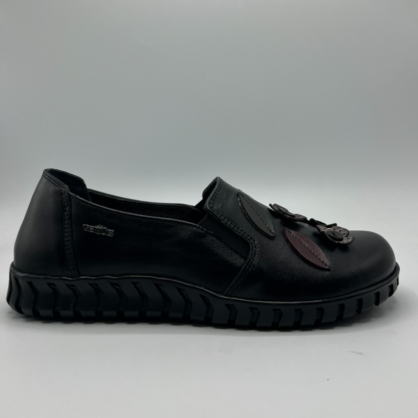 Black shoe with leather accents on a gray background