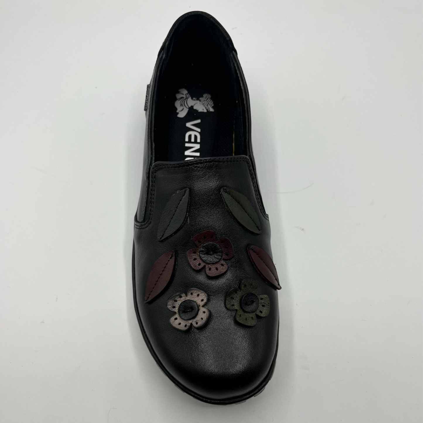 Black slip-on shoe with floral designs on a white background