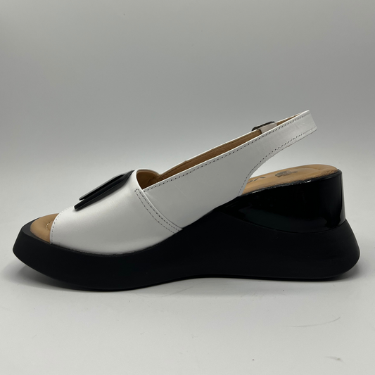 Left facing view of a white leather wedge sandal with an adjustable slingback strap and a contrasting black wedge heel.