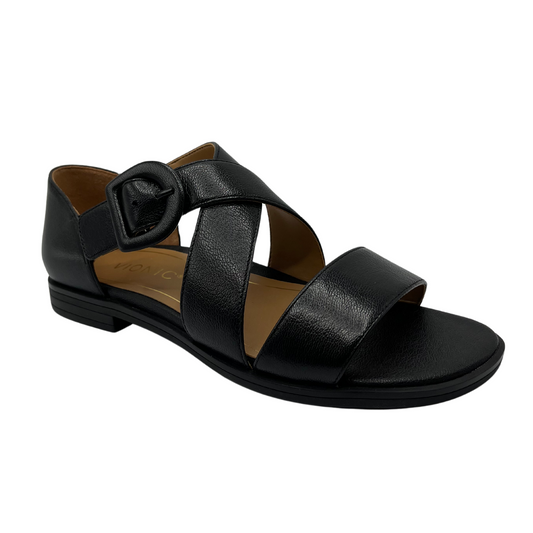 45 degree angled view of black leather sandal with matching buckle and low heel