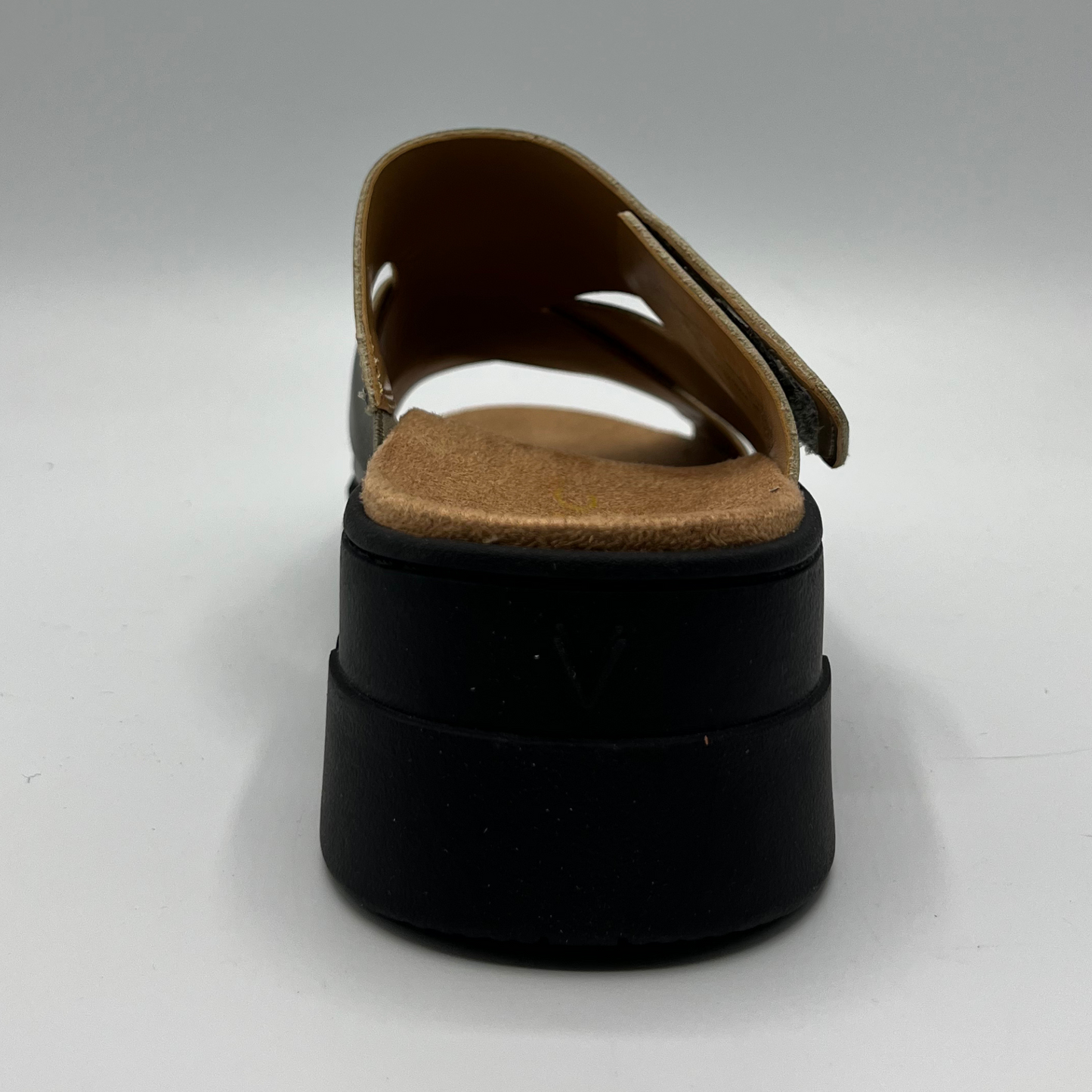 Back facing view of a leather strapped sandal with an adjustable hook and loop strap and a black wedge heel.