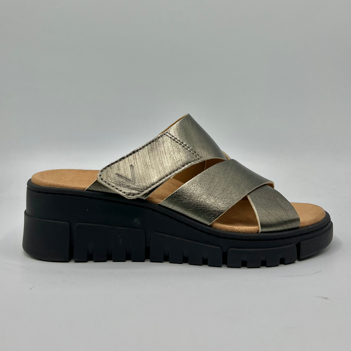 Right facing view of a leather strapped sandal with an adjustable hook and loop strap and a black wedge heel.