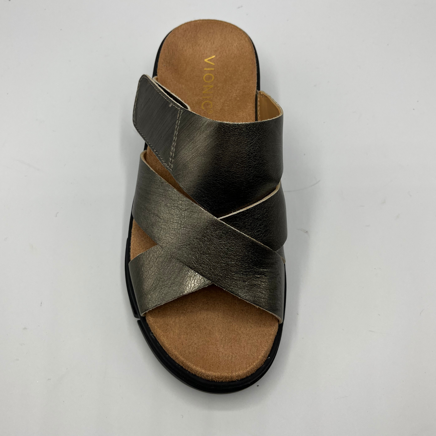 Top facing view of a leather strapped sandal with an adjustable hook and loop strap and a black wedge heel.