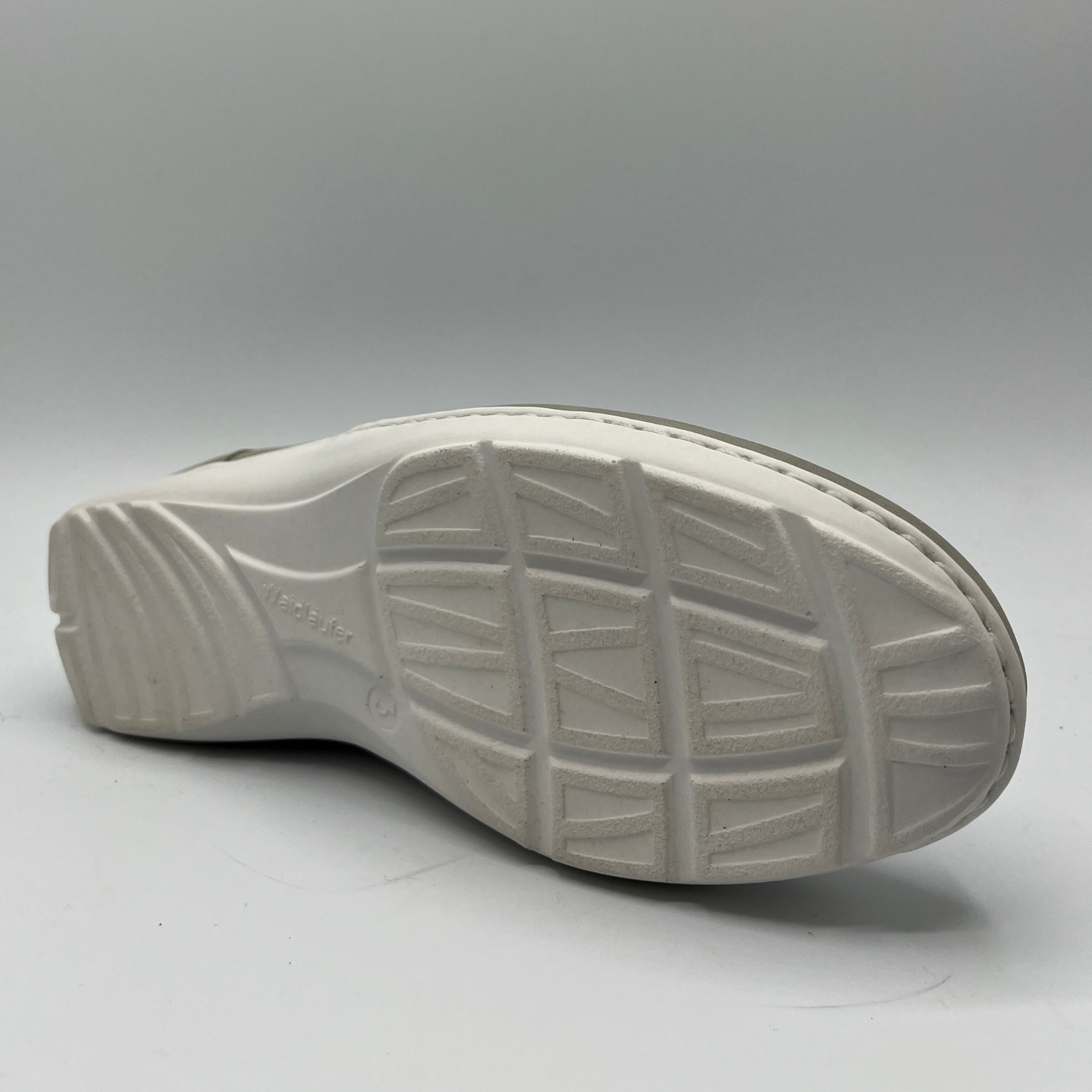 Bottom view of a grey sneaker with a velcro strap and a contoured footbed.