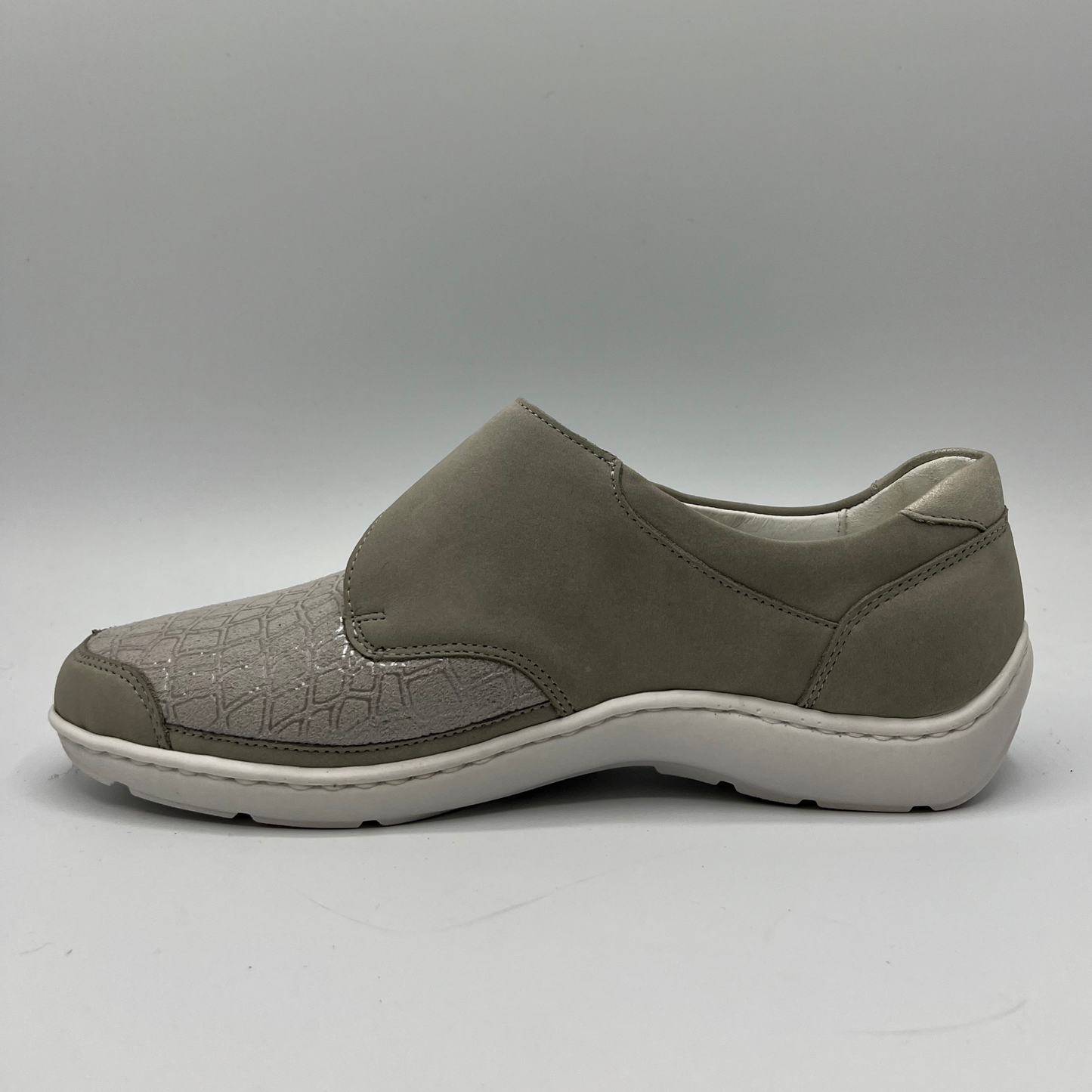 Left facing view of a grey sneaker with a velcro strap and a contoured footbed.