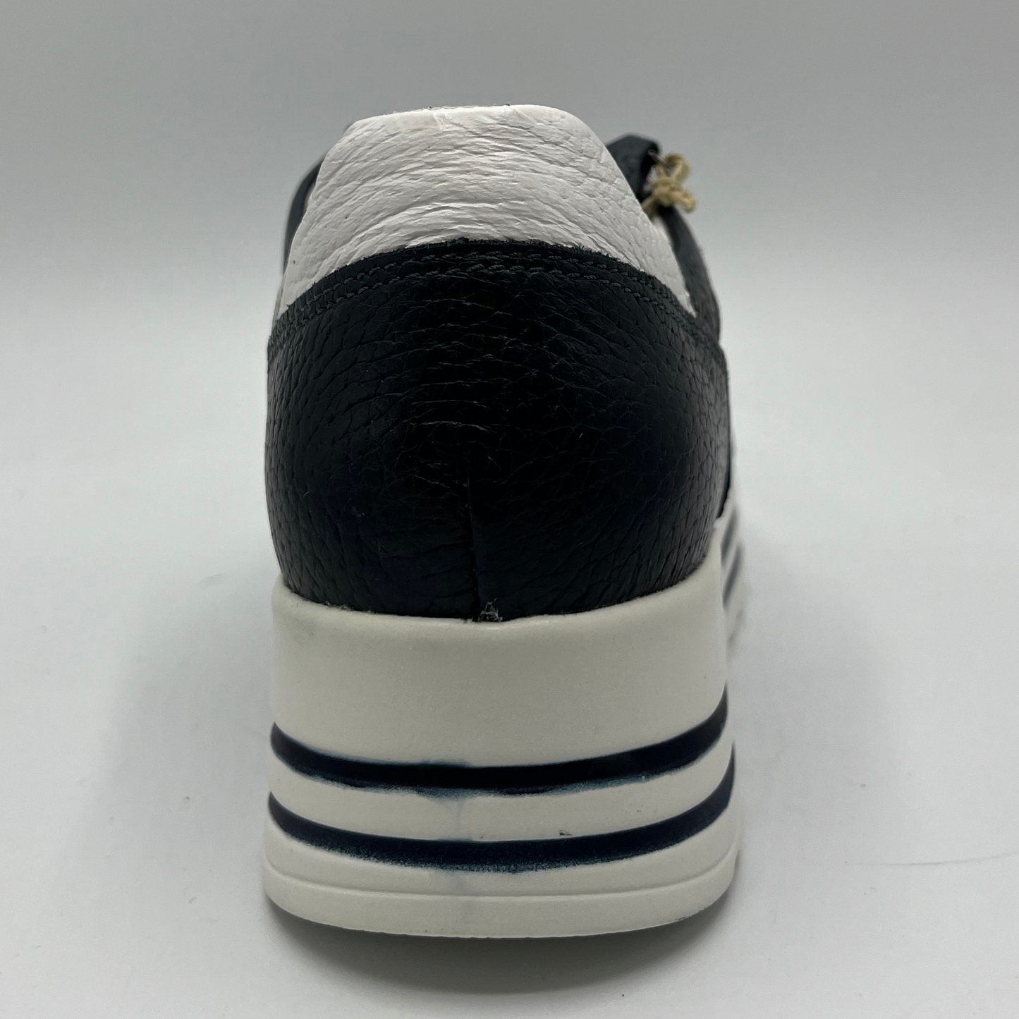 Back view of a navy leather sneaker with a white rubber outsole with laces and a side zipper closure.