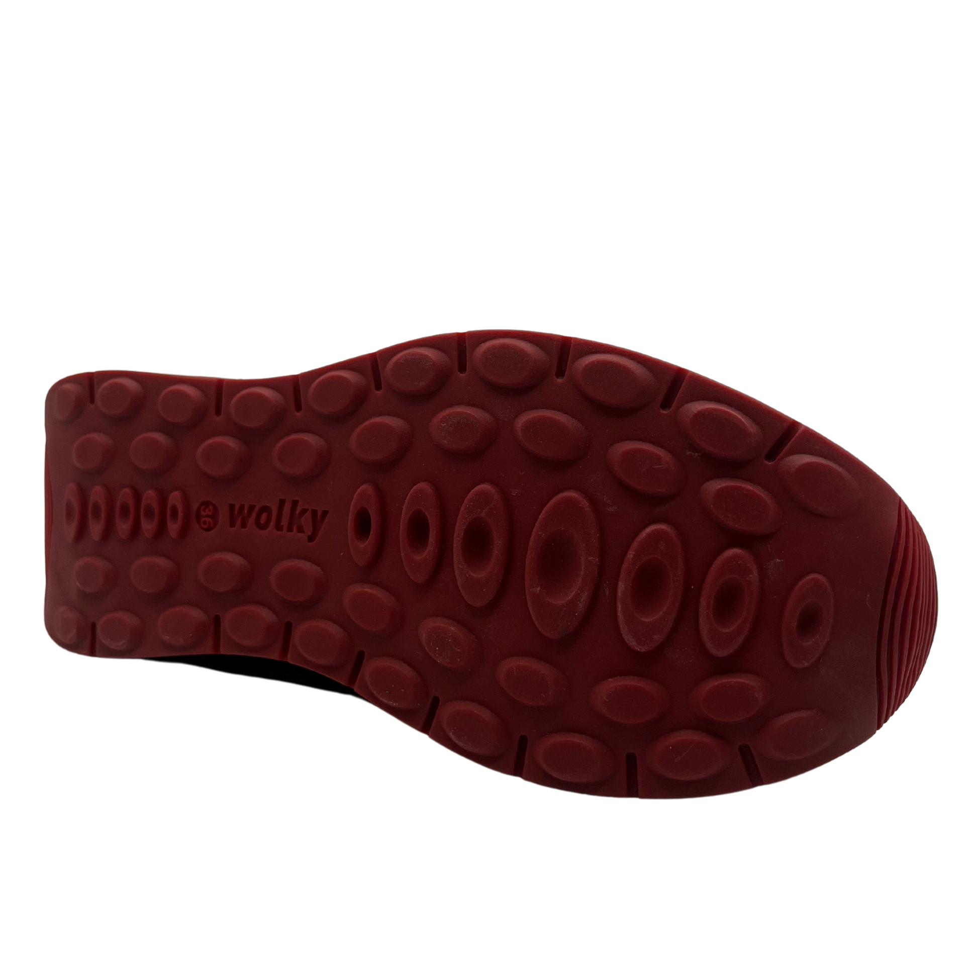 Bottom view of red leather sneakers with a water resistant upper, laces and side zipper closure.