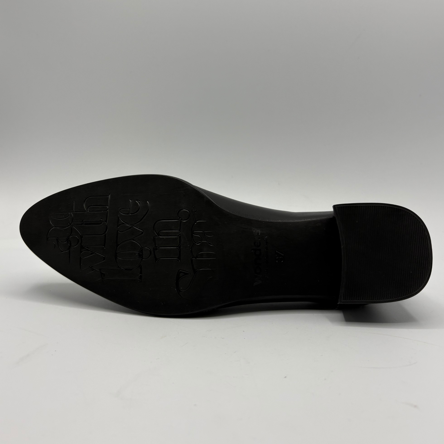A black leather shoe sole with embossed branding, photographed from underneath against a neutral gray background.