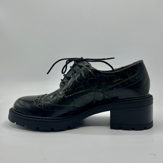 Black leather shoe with crocodile texture on a gray background