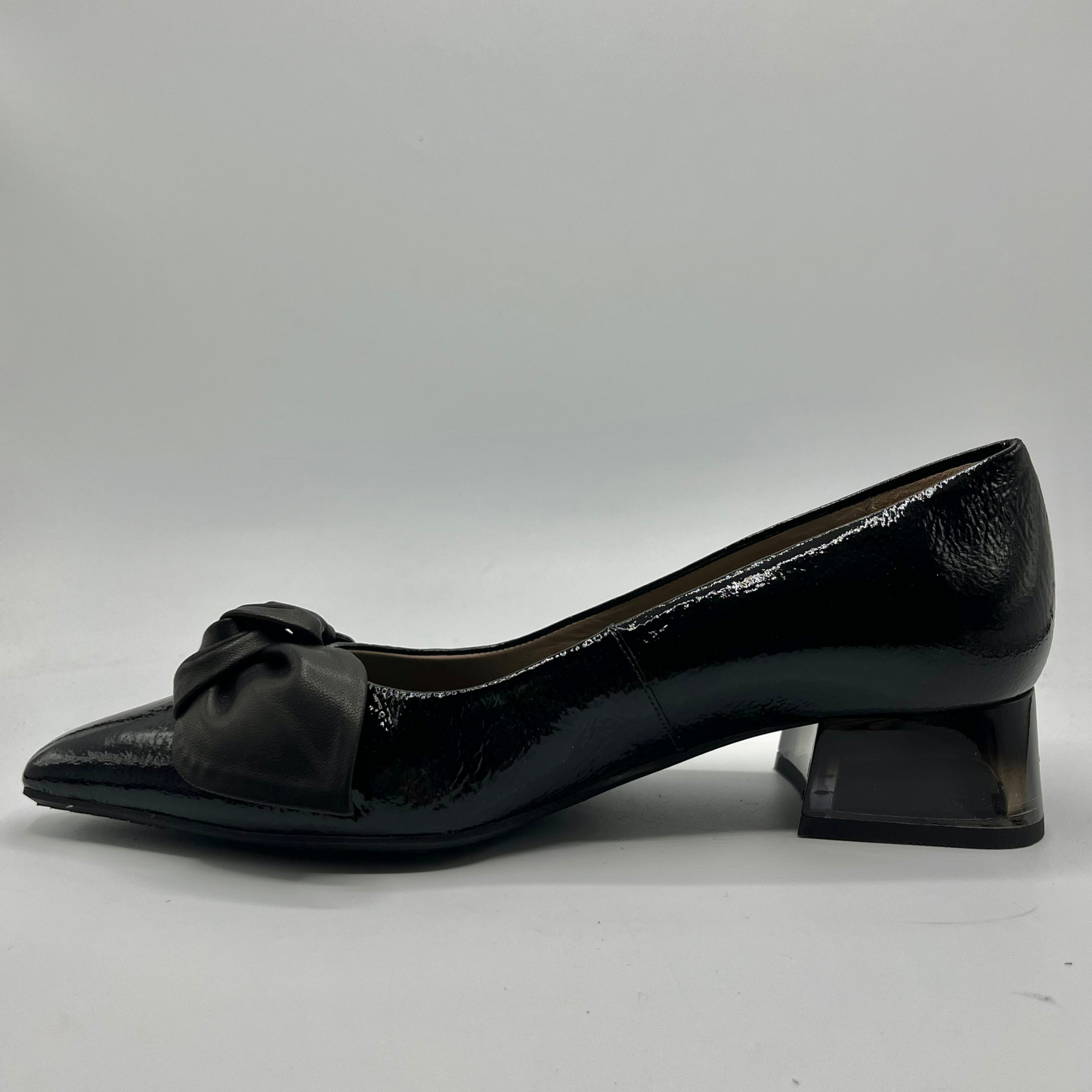 Black patent leather shoe with a bow on a white background