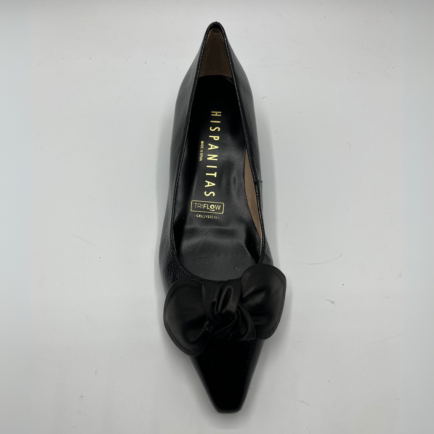 Black pointed-toe shoe with bow detail on a white background
