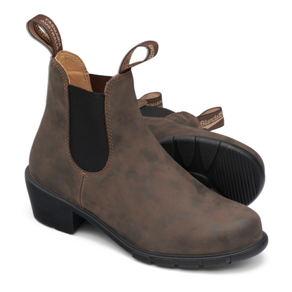 A pair of rustic brown, heeled boots with black soles, black elastic sides and tan coloured leather interior lining.