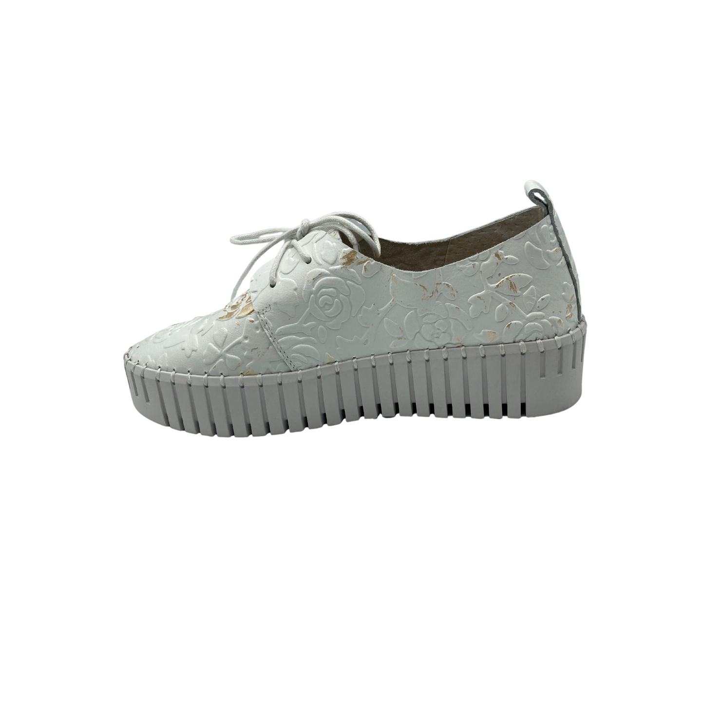Inside view of a sneaker style loafer. Upper is an embossed white leather with florals. Sole is an elevated rubber