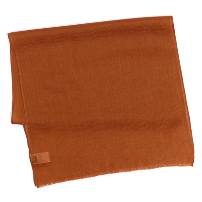 A plain burnt orange scarf is pictured folded.