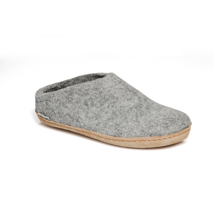 A felted light grey slipper pictured at a slight angle, showing part of the top front and side of the slipper. A tan leather sole lines the bottom of the shoe with a row of stitching. 