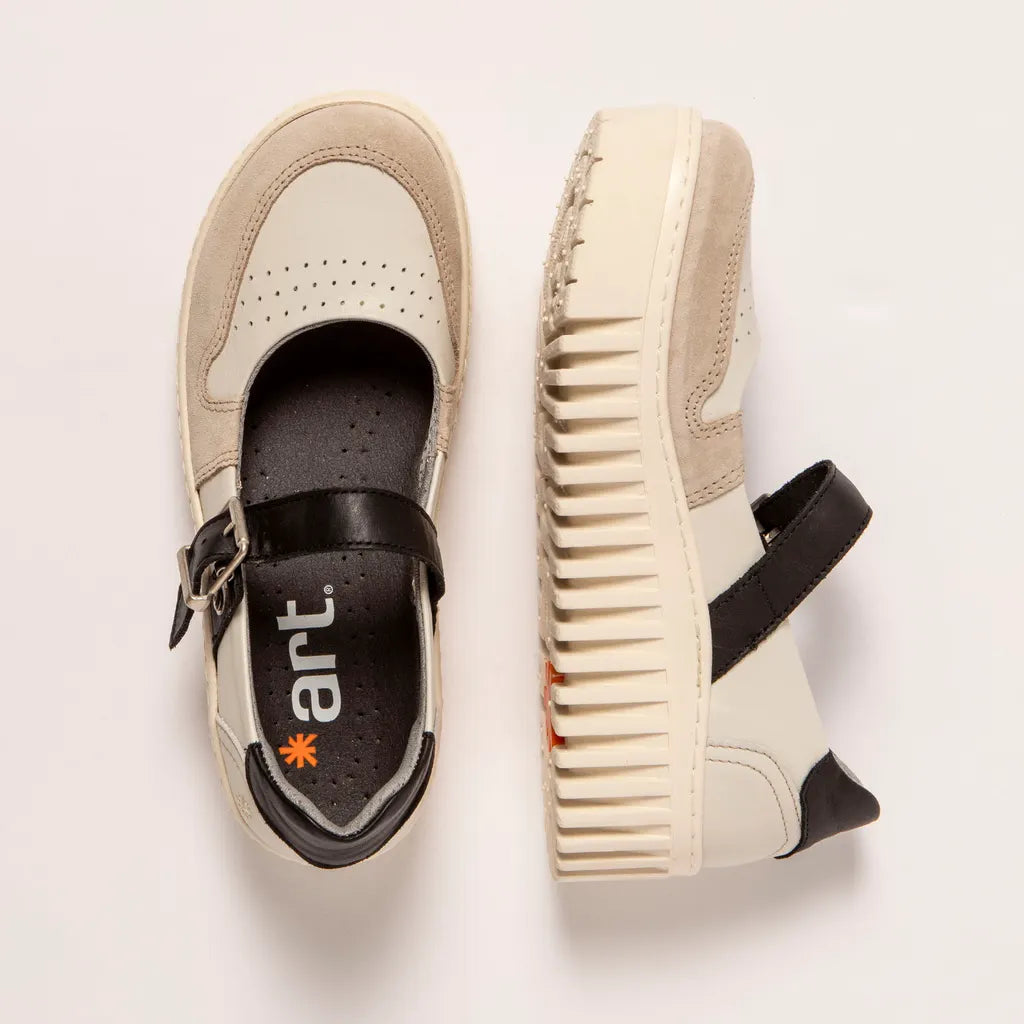 Pair of beige mary jane sneakers with black buckles on a light background