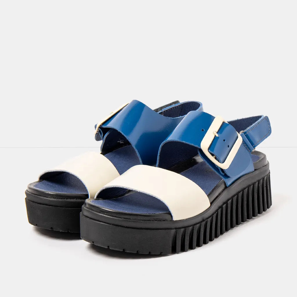 Blue and white sandals with thick black soles on a light gray background