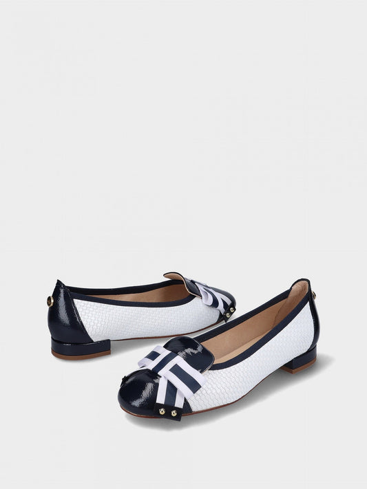 Pair of white and navy flat shoes on a light gray background