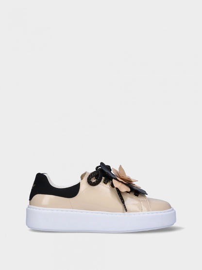 Beige sneaker with black accents and a floral detail on a white background