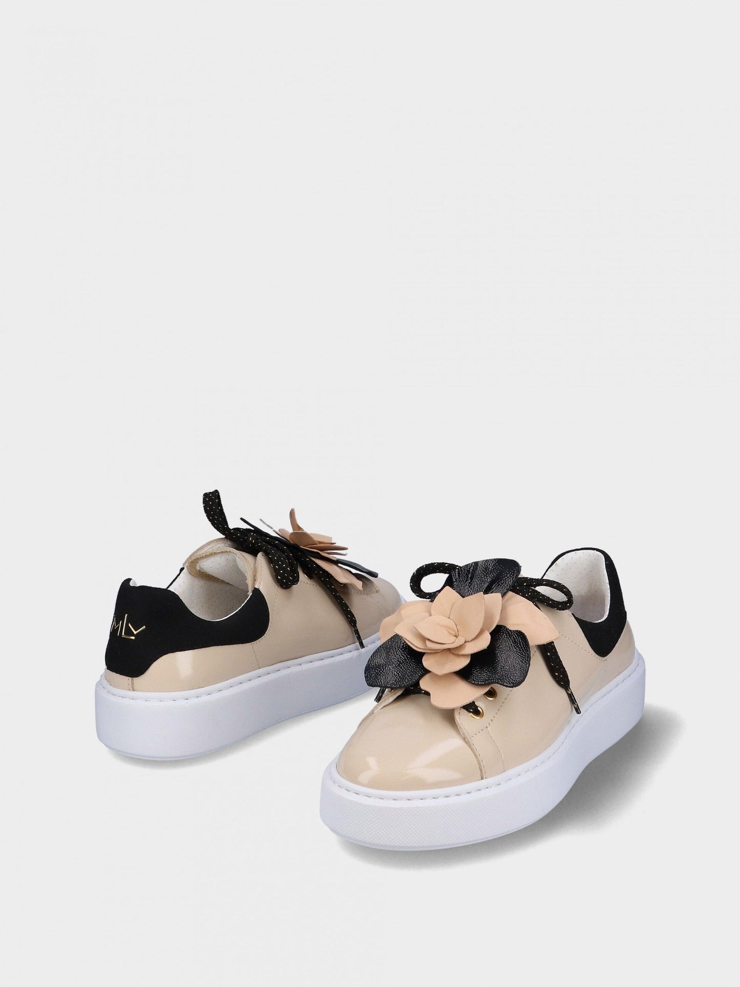 Pair of beige sneakers with black laces and floral details on a white background