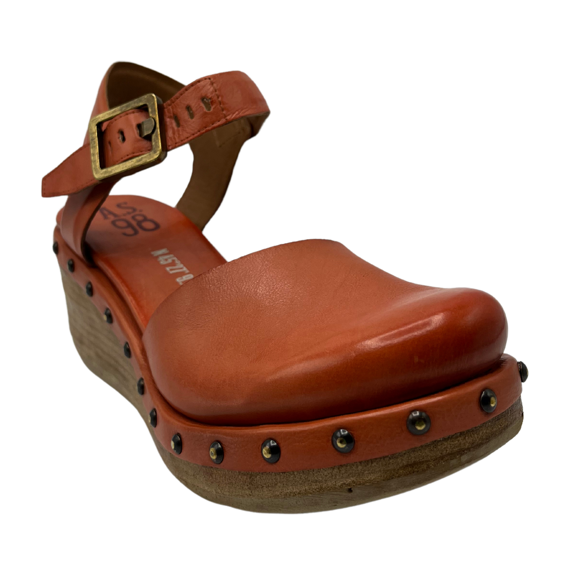 45 degree angled view of orange wedge shoe with rounded toe and studded details around 
