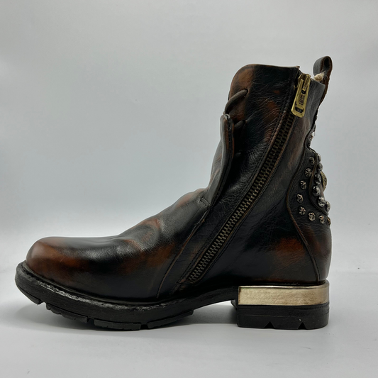 Left facing view of a brown and black burnished short boot with a gold accent on the heel and metallic embellishments along the shaft.
