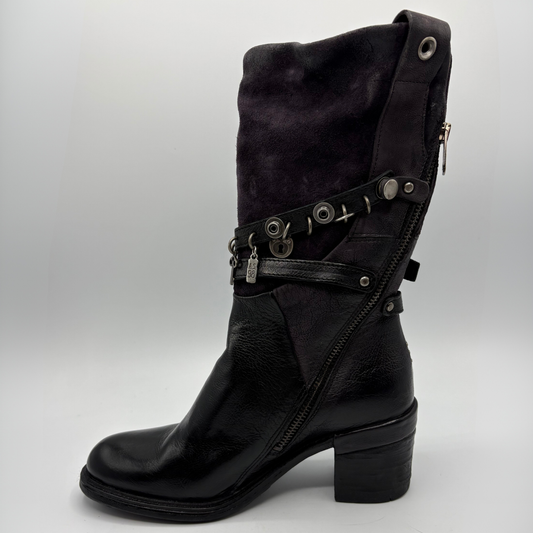 Left view of a black tall boot with a metal embellishments and a rubber outsole