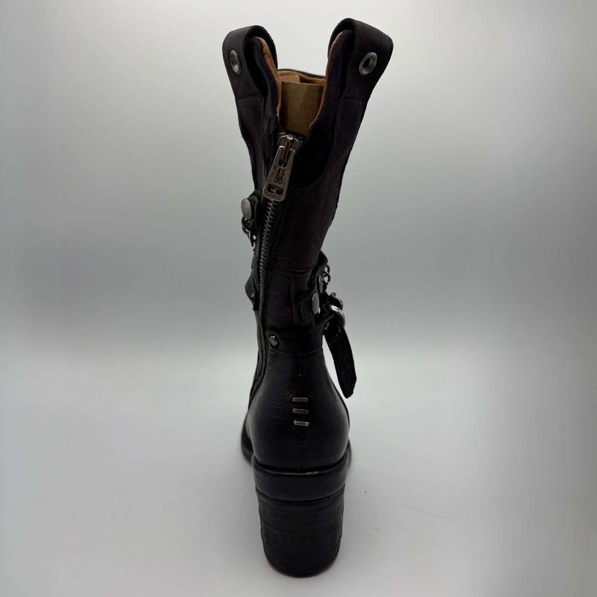 Back view of a black tall boot with a metal embellishments and a rubber outsole