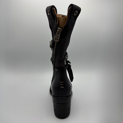 Back view of a black tall boot with a metal embellishments and a rubber outsole