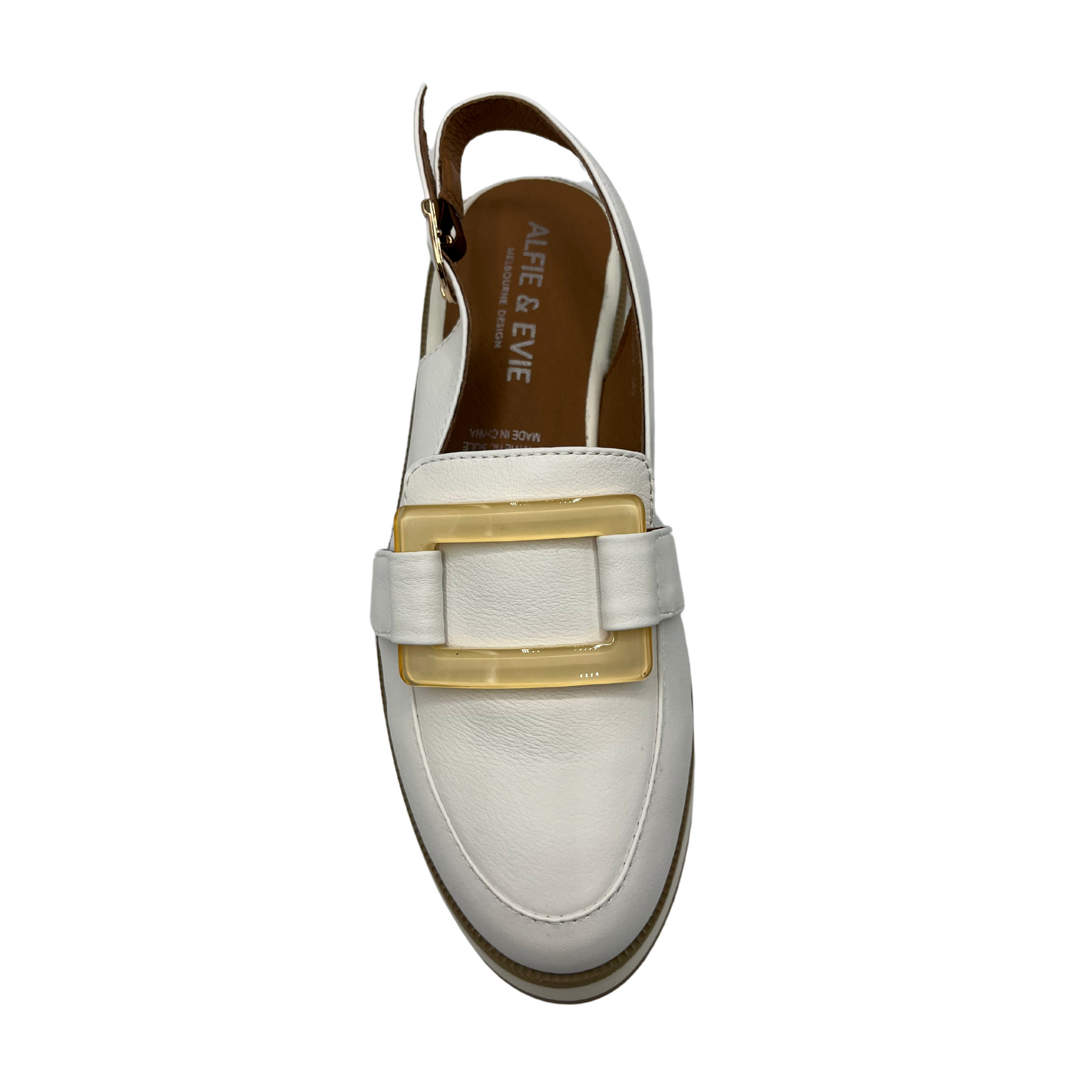 Top view of white leather slip on loafer with adjustable sling back strap, opaque square gold detail on upper and white wedge outsole.