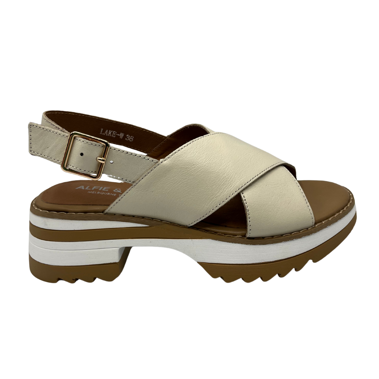 Right facing view of cream leather sandals with a cross strap design, chunky sole and adjustable sling back strap.