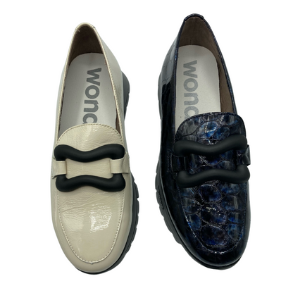 Top down view of one cream coloured and one blue coloured loafer. Both with black buckle detail