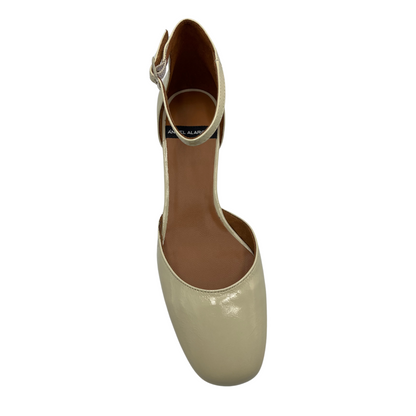 Top view of a patent leather pump in off white. Featuring a delicate ankle strap, rounded toe and flared block heel.