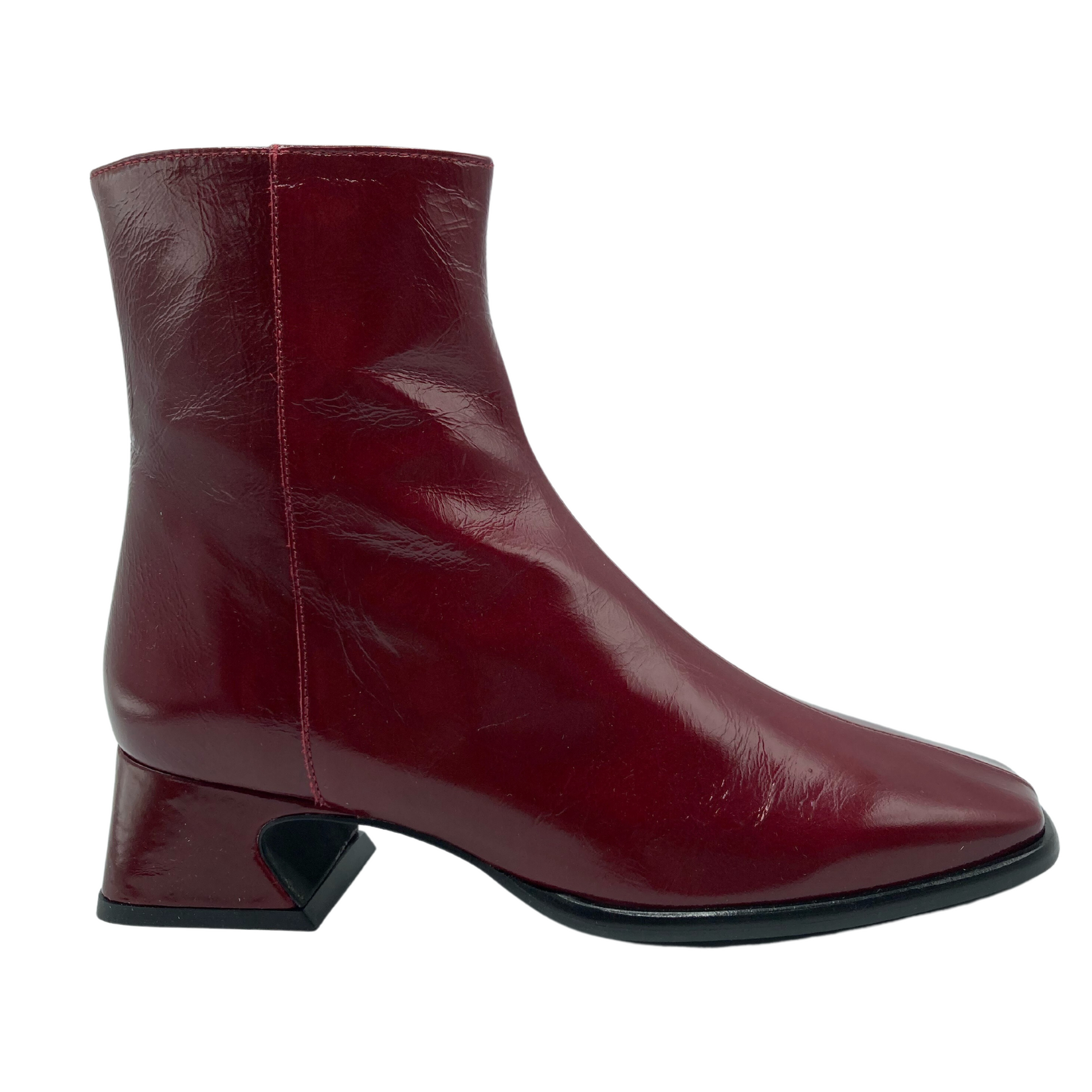Right facing view of red leather short boot with flared heel and black sole