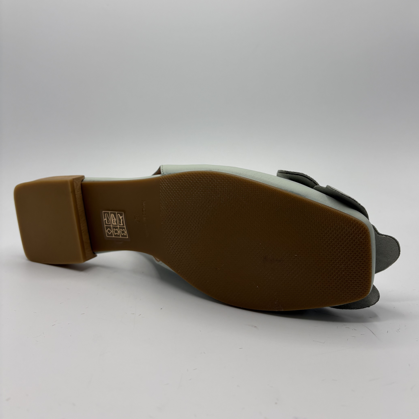 Back view of a shoe with a brown sole on a white background