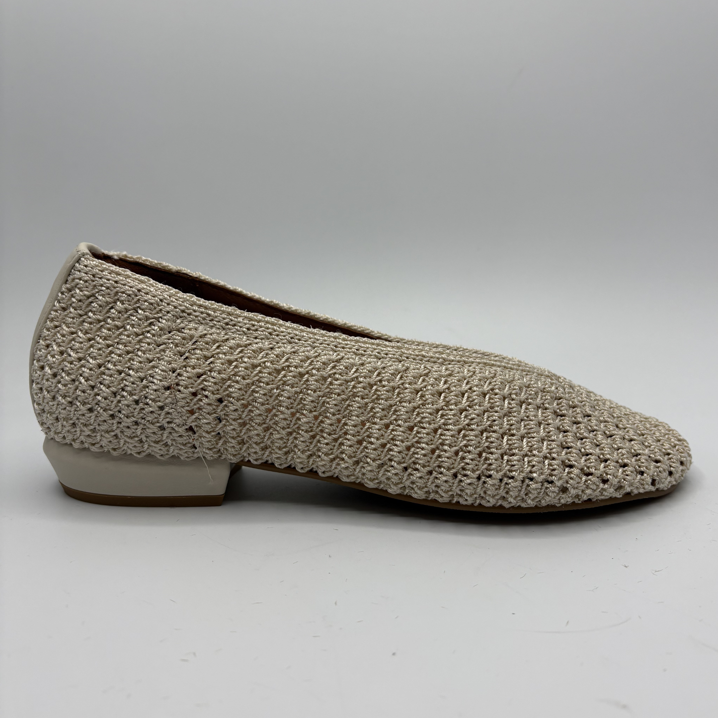 Beige woven flat shoe on a white background