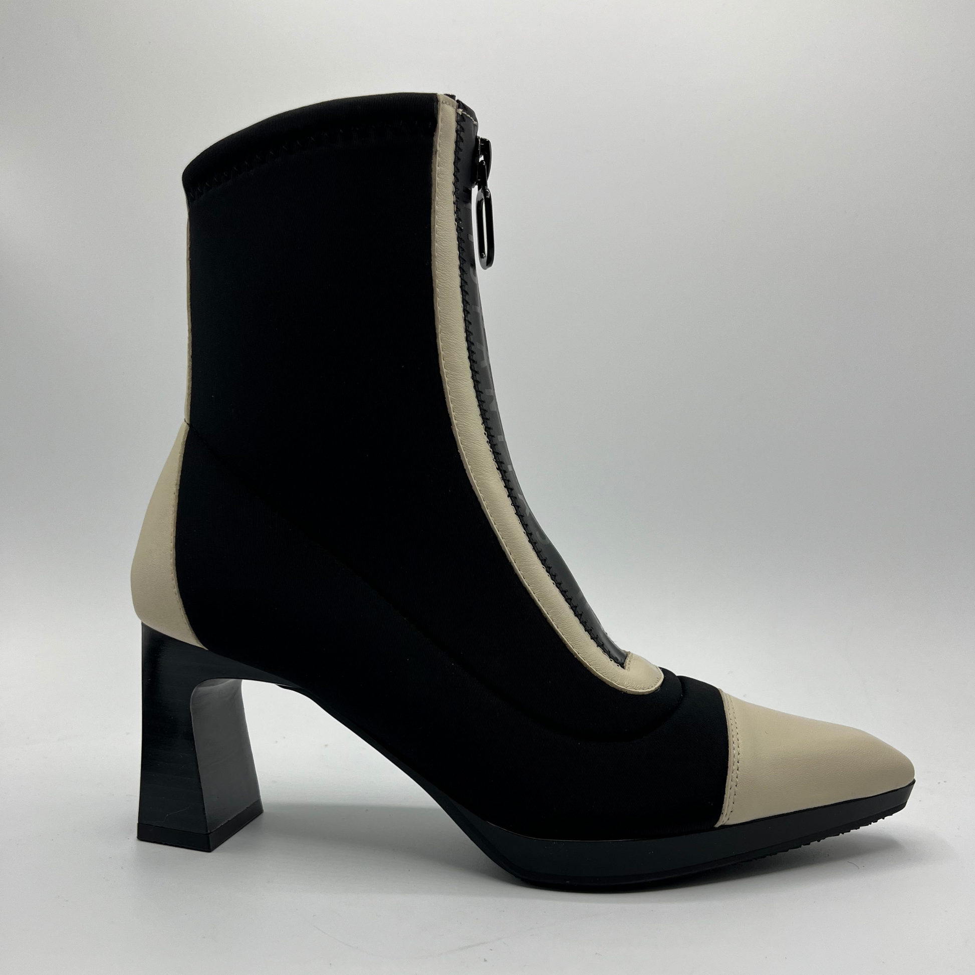 Black and beige ankle boot with a block heel on a light gray background