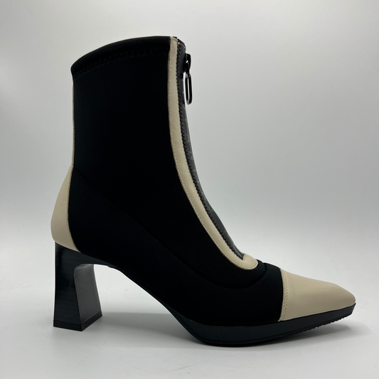 Black and beige ankle boot with a block heel on a light gray background