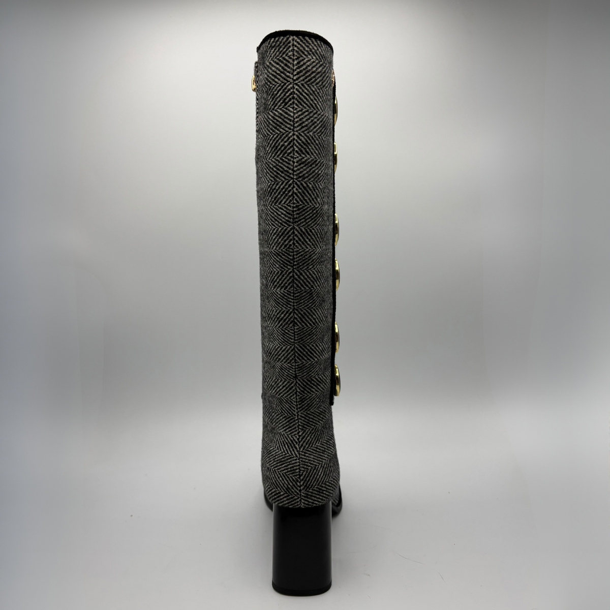 Back view of a tweed patterned tall boot with large black and gold buttons and a block heel