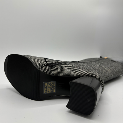 Bottom view of a tweed patterned tall boot with large black and gold buttons and a block heel