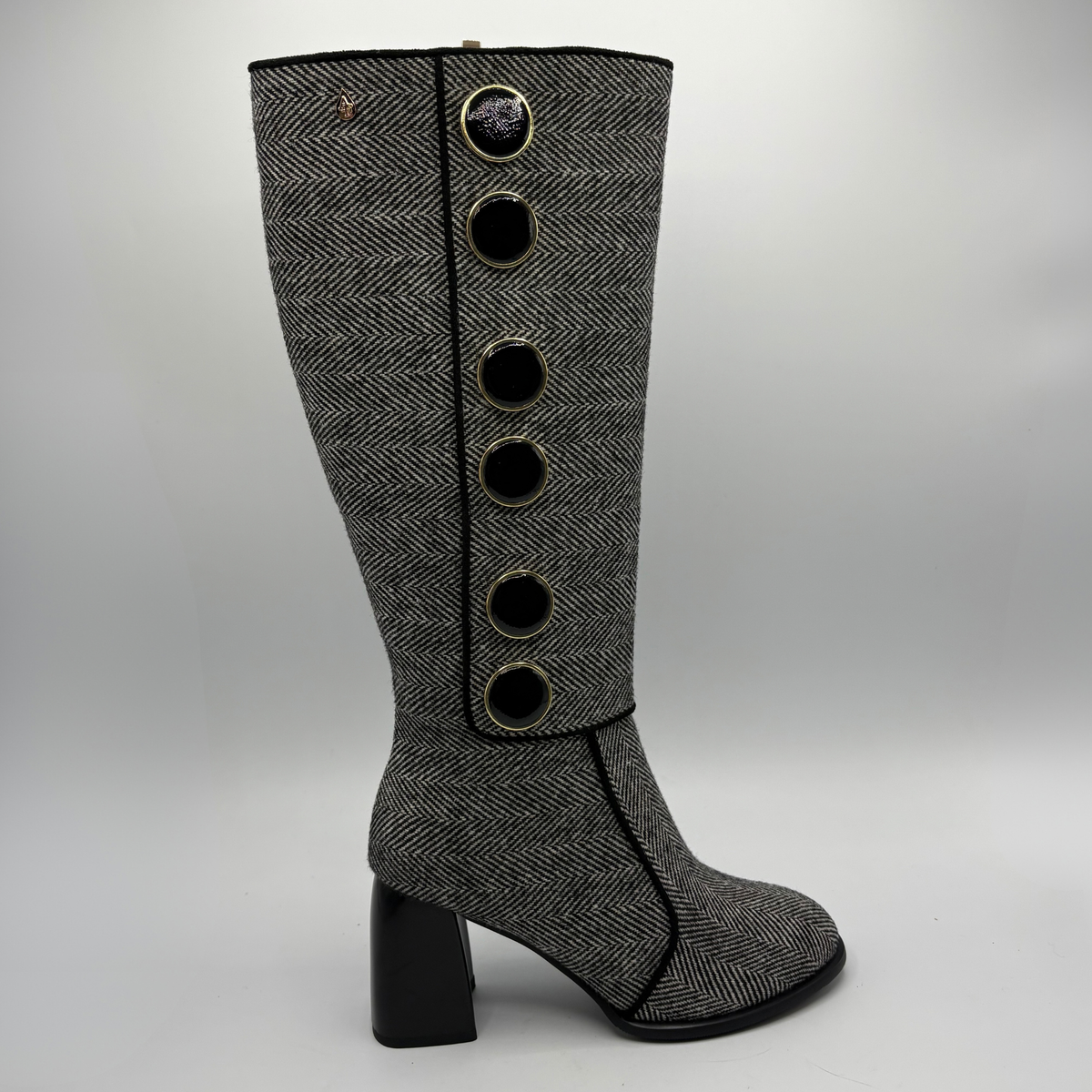 Right facing view of a tweed patterned tall boot with large black and gold buttons and a block heel