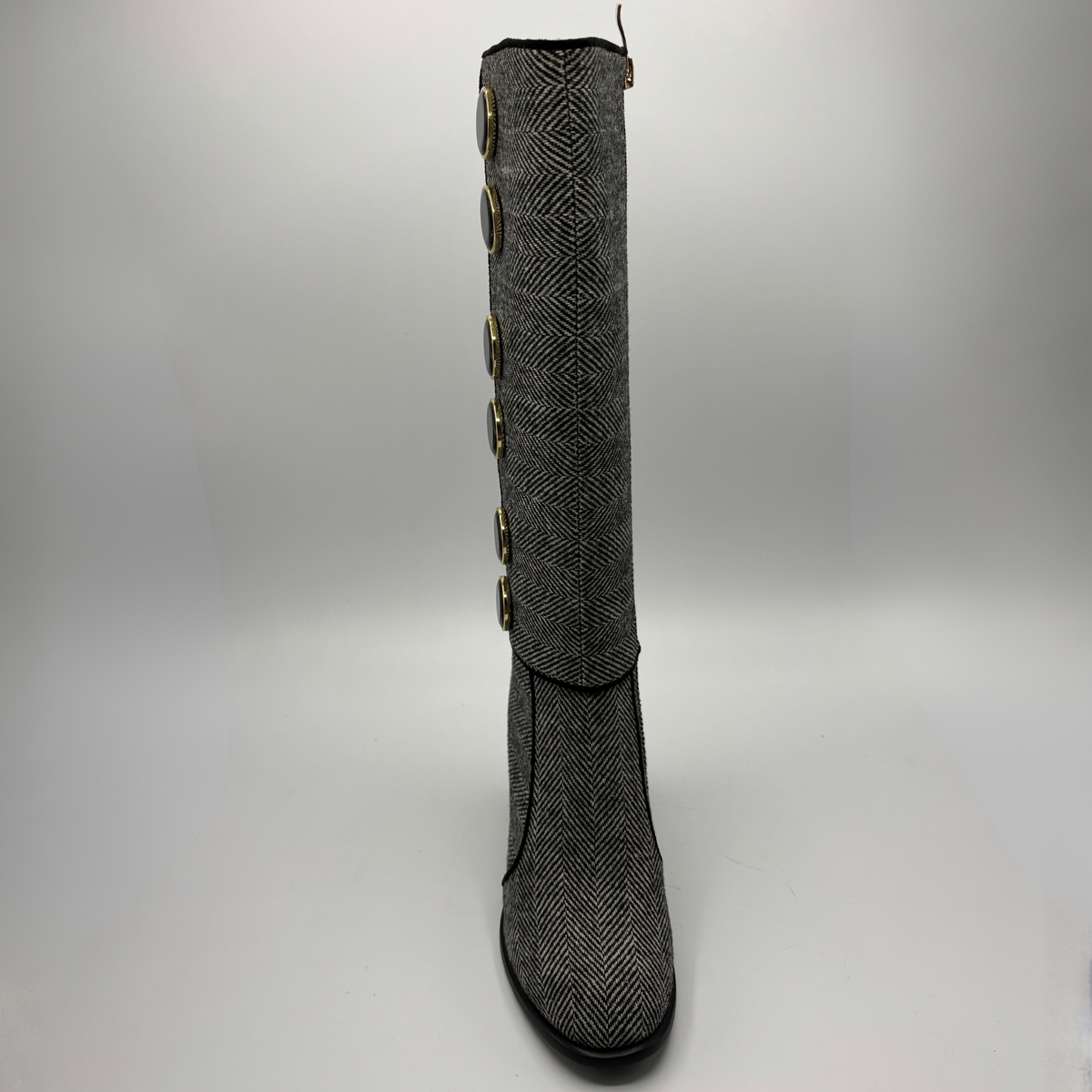 Front view of a tweed patterned tall boot with large black and gold buttons and a block heel