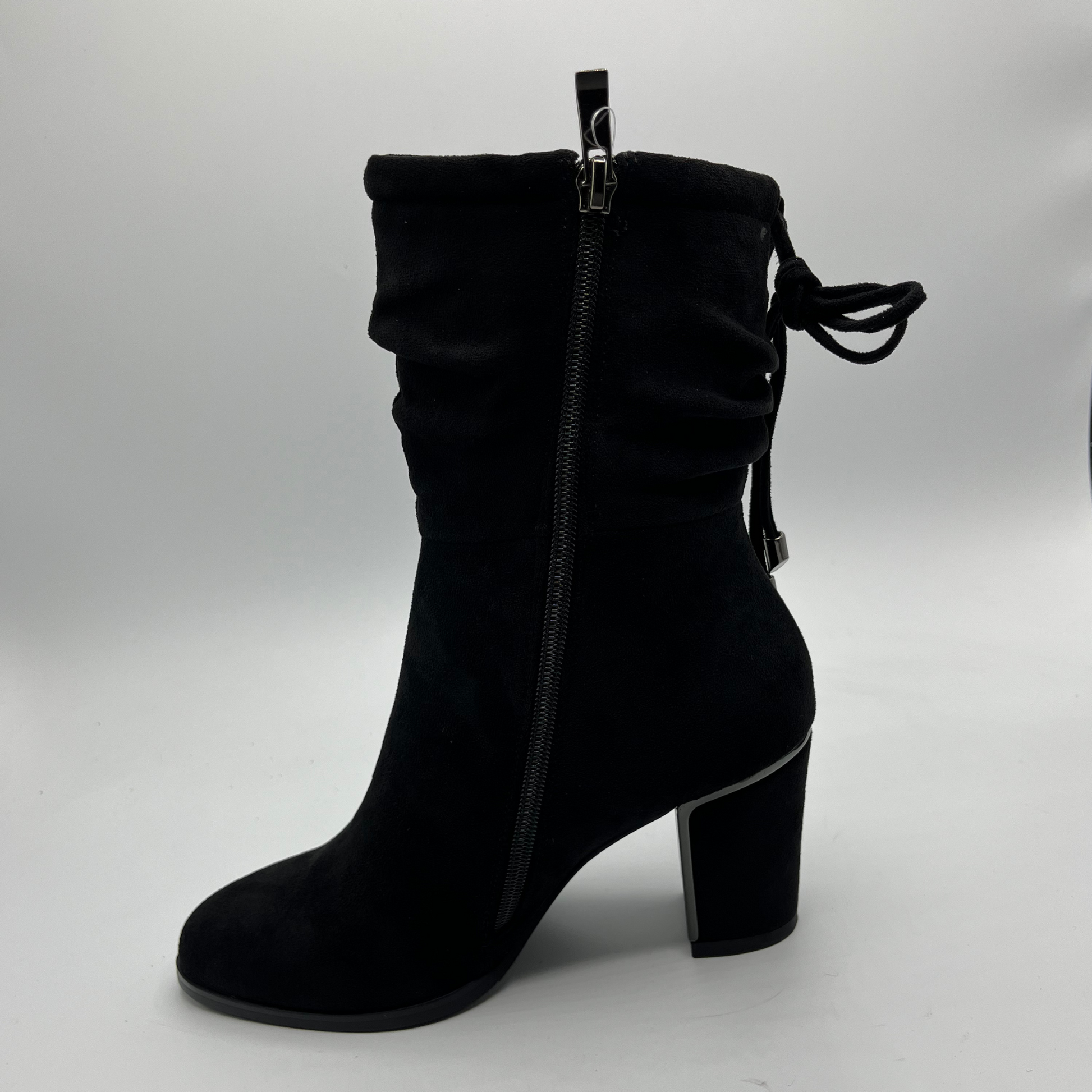 Black suede ankle boot with a block heel on a light gray background