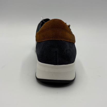A single low-top sneaker shown from the back, featuring a dark navy blue suede upper, a contrasting brown suede heel tab, and a thick white midsole.
